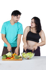 Obraz na płótnie Canvas Man and pregnant woman preparing salad