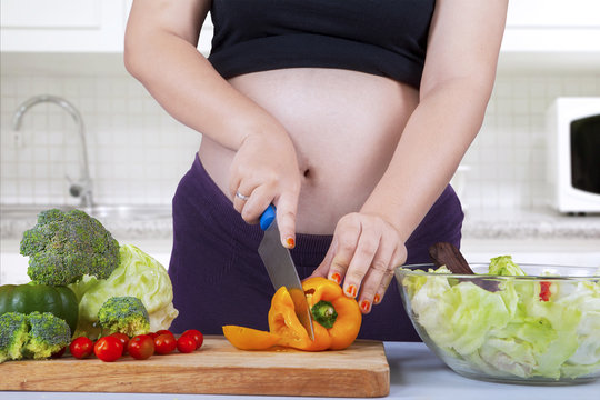 Pregnant woman cooking salad
