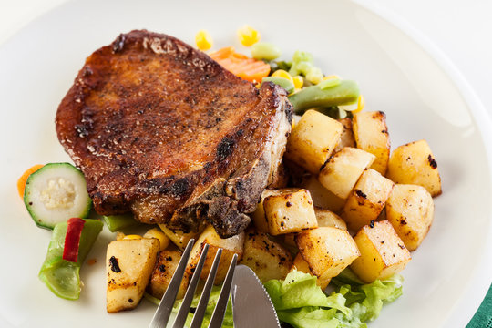 Fried pork with potatoes and vegetables salad
