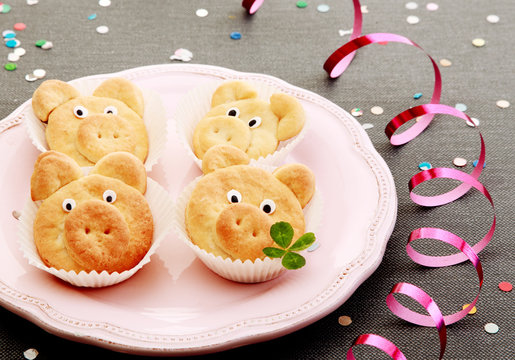Tasty cute pig cookies with leaves on pink plate