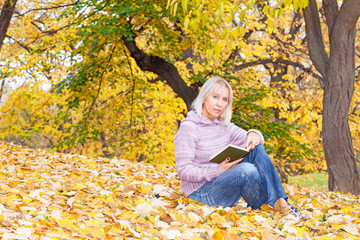 Good looking mature woman reading a book in the park