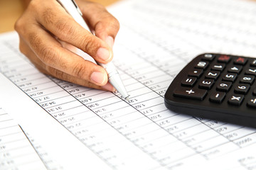 Close up woman hand holding pen on spreadsheet