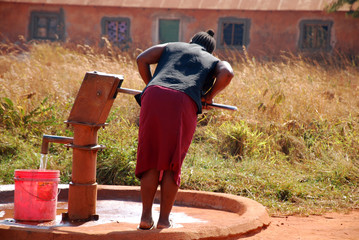 A woman and pump water from a public fountain-Pomerini-Tanzania-
