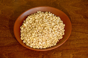 Cedar pine nuts in a ceramic plate on a wooden background