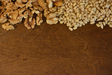 Walnuts and cedar pine nuts on wooden background