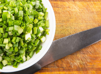 Chopped scallions or spring onion leaves in a white bowl 