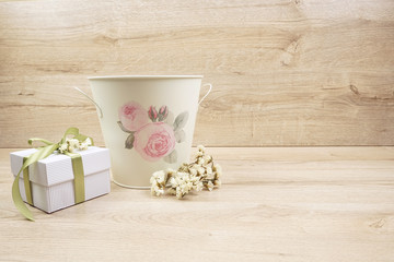 Romantic pot with flower and gift box on wooden background