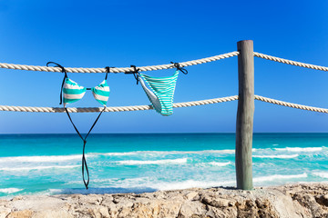 Obraz premium Blue woman's swimming suit hanging on white ropes
