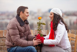 Romantic young man giving flower to his girlfriend