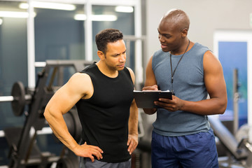 african personal trainer helping man to fill the membership form