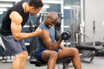 Gordijnen gym trainer motivating client to lift dumbbell © michaeljung