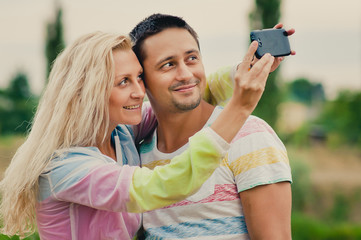 Beautiful young loving couple making selfie by smart phone