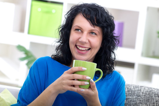 beutiful young woman sitting at her home drinking coffe, smiling