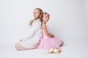 Fototapeta na wymiar Blonde sisters posing with pointes in studio