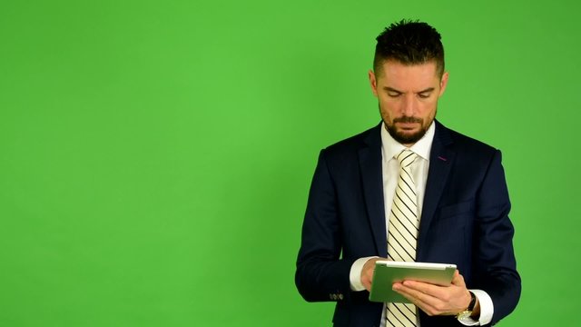 business man works on tablet - green screen - studio