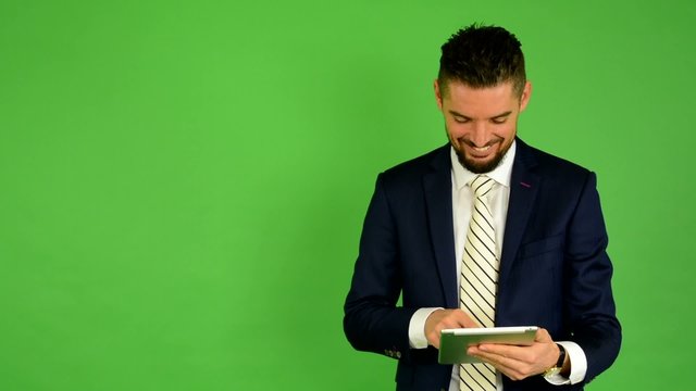 business man works on tablet and smiles - green screen - studio