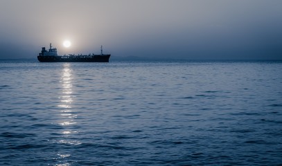 Moon rising above a sailing cargo ship