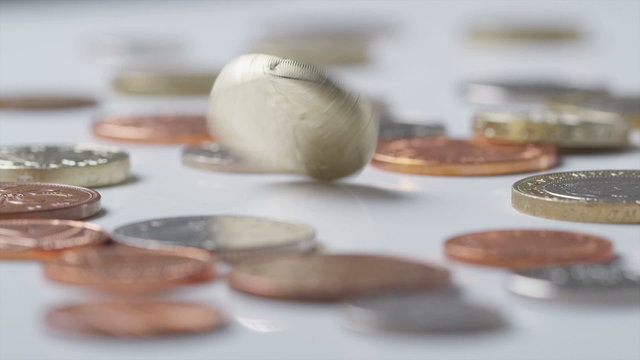 UK One Pound coin spinning amongst other coins in slow motion