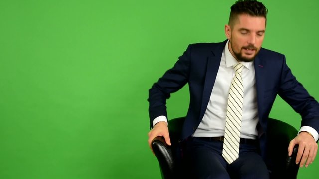 business man goes to sit down and smiles - green screen - studio