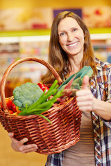 Frau mit Korb voller Gemüse hält Daumen hoch