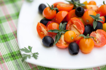 Fototapeta na wymiar Salad with tomatoes, olives and basil on a plate