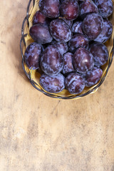 plums in a basket on a wooden background