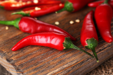 Red hot chili peppers on wooden board, on sackcloth background