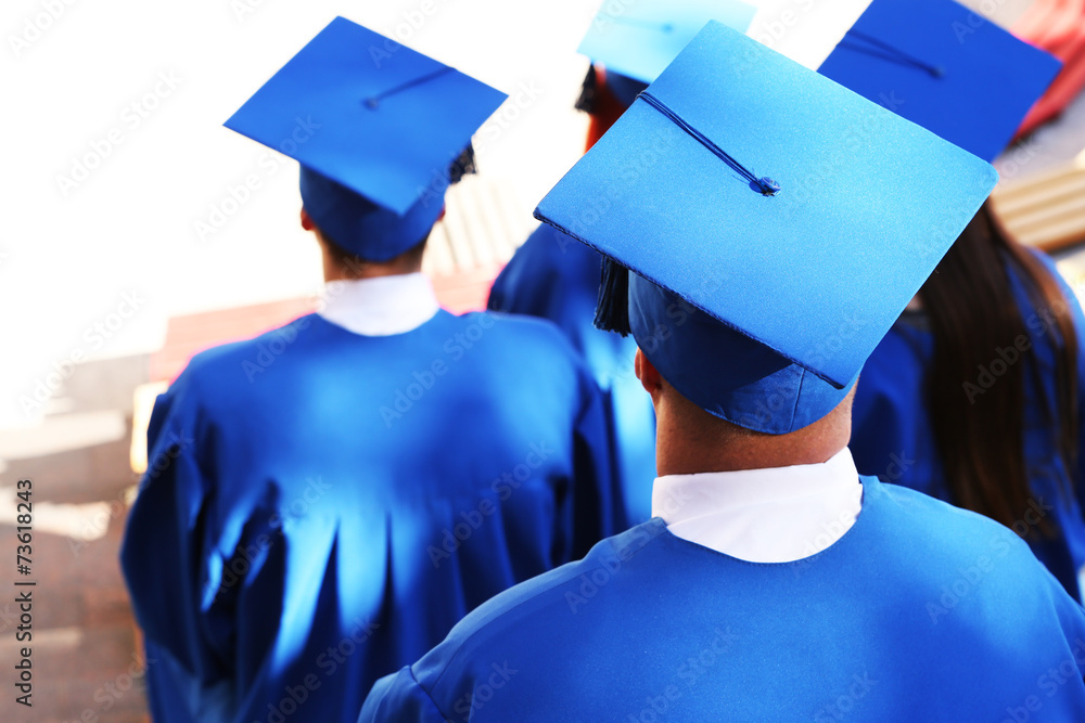 Poster Graduate students wearing graduation hat and gown, outdoors