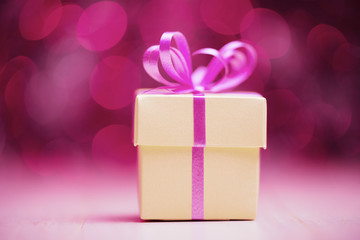 Gift box with pink bow against defocused lights