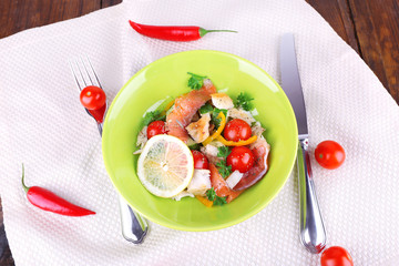 Appetizing fish salad with vegetables on plate on table