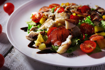 Appetizing fish salad with vegetables on plate close-up