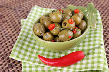 Green olives in oil with spices and rosemary in bowl