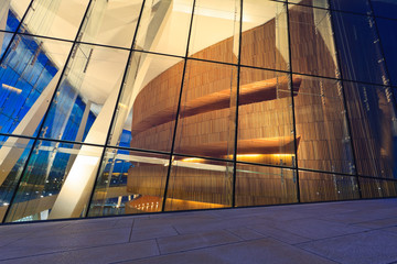 A view of the lighted balcony and pillars through the windows in to inside of the new Oslo opera house from the top of the roof in the evening