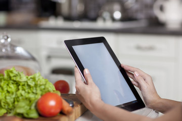 female hands holding a laptop at the dining table in the kitchen
