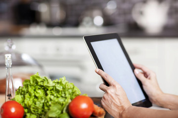 female hands holding a laptop at the dining table in the kitchen © Denizo