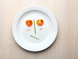 Vegetable face on plate on wooden table