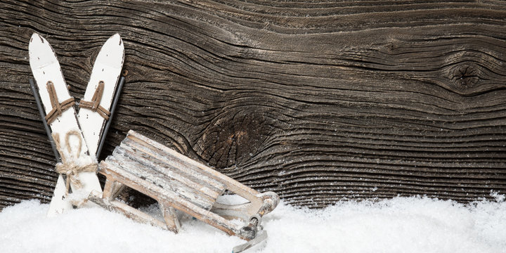 Wintersport Ski und Schlitten vor Holzwand