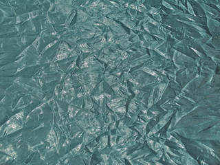 Obraz premium Texture of shiny fabric with creased folds in turquoise color