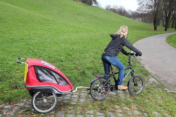 Mutter auf Fahrrad mit Kinderanhänger und E-Bike