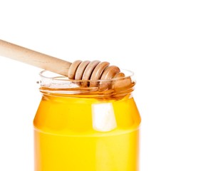 honey jar on white background with wooden dipper inside