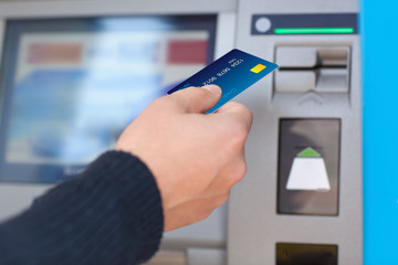 man puts credit card into ATM