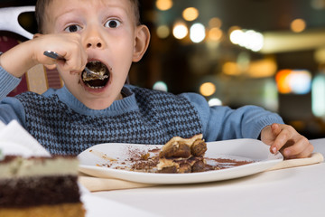 Hungry little boy gobbling down a slice of cake