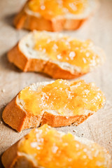 pieces of baguette with orange marmalade closeup on wooden board