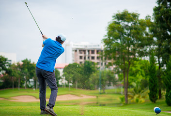 Golfer hits an fairway shot towards the club house