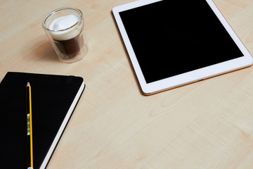 Tablet with blank screen, organiser and coffee on a wooden desk