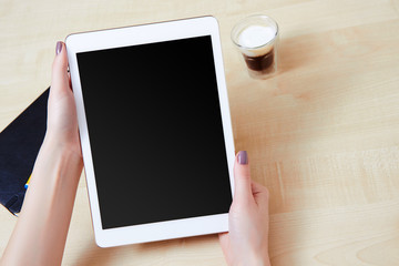 Girl holding a tablet pc at work place with a coffee
