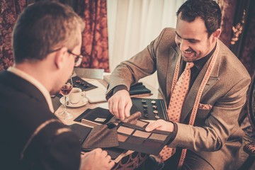 Tailor and client choosing mterials for custom made suit