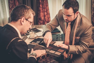 Tailor and client choosing mterials for custom made suit
