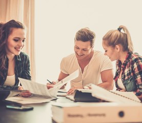 Students preparing for exams in apartment interior behind table