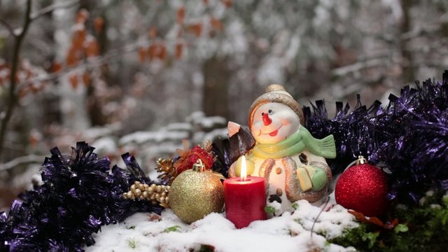 Christmas decoration with burning candle and snowfall